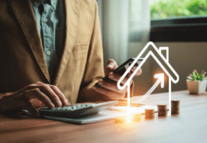 Person using calculator and phone beside stacked coins with rising property icon overlay
